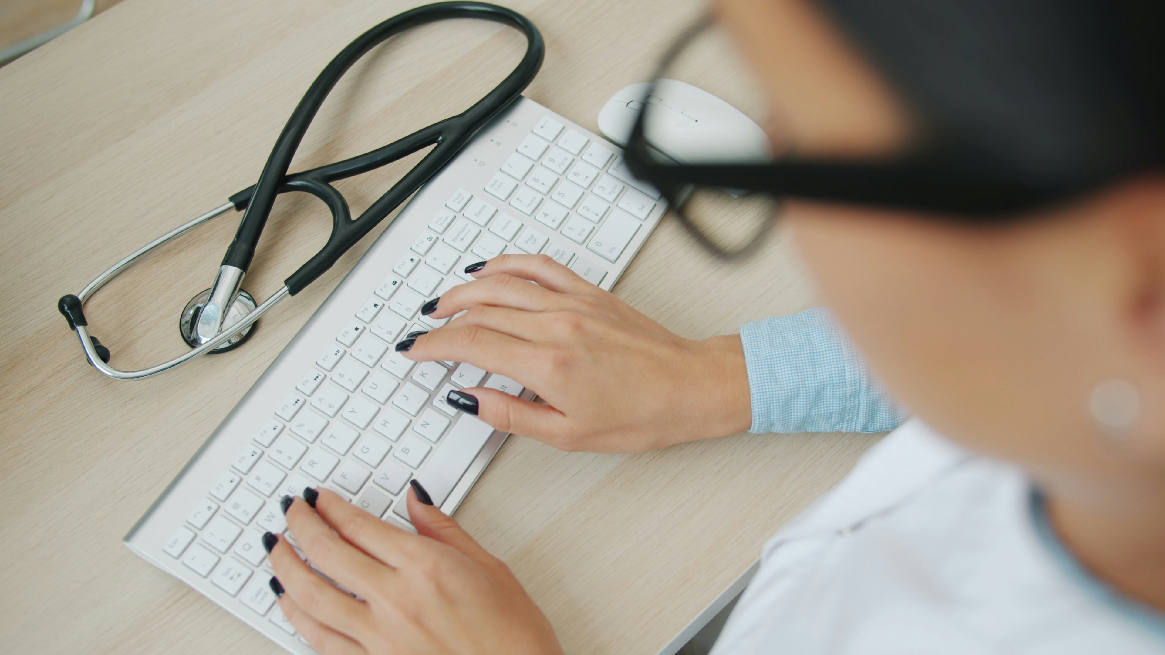 Healthcare professional working at computer with stethoscope, representing medical billing and revenue cycle management